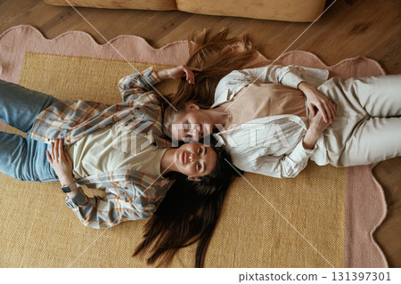 Lying down on the floor. Two happy young female best friends are indoors 131397301