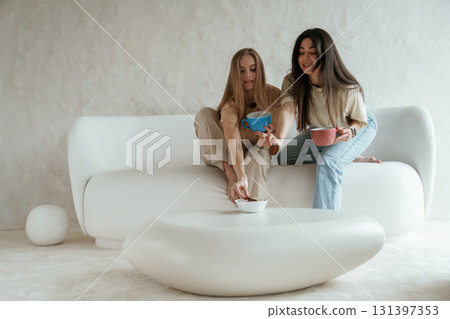 Tea and cookies. Two happy young female best friends are indoors 131397353