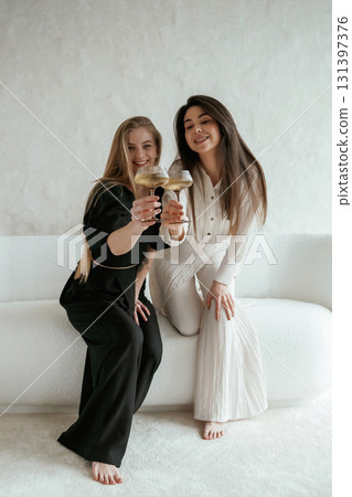 Event, with drinks, celebrating. Two happy young female best friends are indoors 131397376