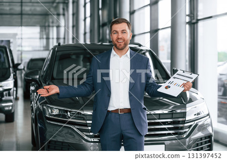 With notepad. A businessman is in a car dealership 131397452