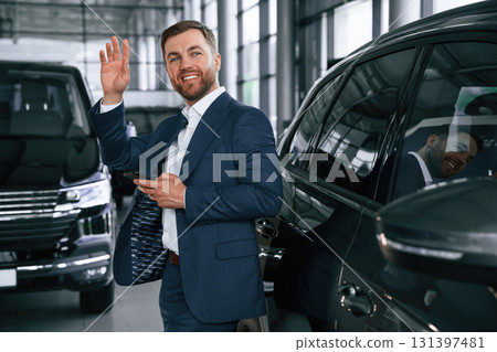 Hello hand gesture. A businessman is in a car dealership 131397481