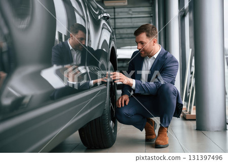 Checking the wheel. A businessman is in a car dealership 131397496