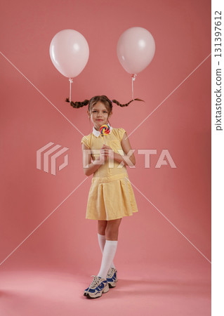Balloons are on the pigtails. Cute little girl is against pink background Balloons are on the pigtails. Cute little girl is against pink background 131397612