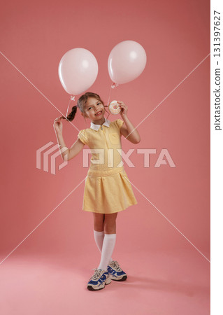 Donut in hand. Cute little girl is against pink background Donut in hand. Cute little girl is against pink background 131397627