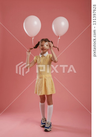 Donut in hand. Cute little girl is against pink background 131397628