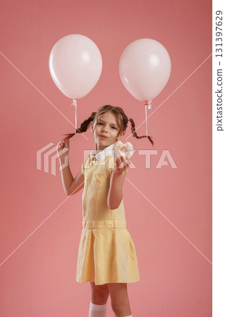 Donut in hand. Cute little girl is against pink background 131397629