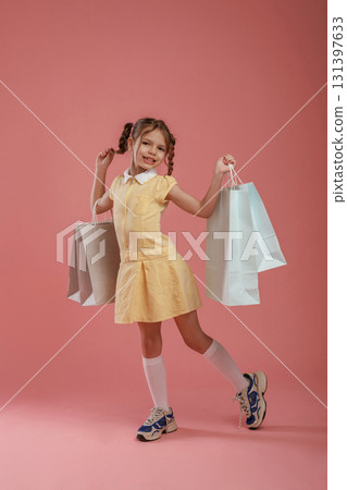 With shopping bags. Cute little girl is against pink background 131397633