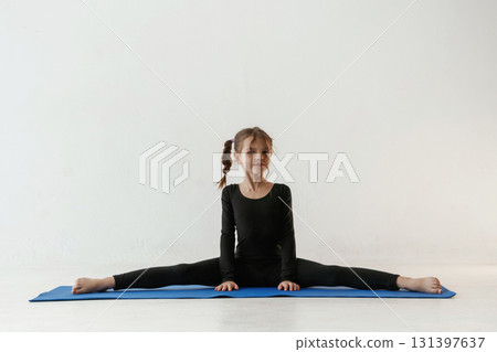 On the twine. Little girl in yoga clothes is on the fitness mat On the twine. Little girl in yoga clothes is on the fitness mat 131397637