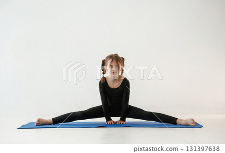 On the twine. Little girl in yoga clothes is on the fitness mat On the twine. Little girl in yoga clothes is on the fitness mat 131397638