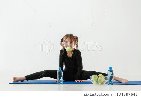 Healthy eating, green apples. Little girl in yoga clothes is on the fitness mat Healthy eating, green apples. Little girl in yoga clothes is on the fitness mat 131397645