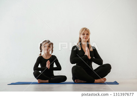 Mother and little daughter are in fitness clothes on yoga mat 131397677