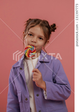 Close up view, with candy. Cute little girl is against pink background 131397773