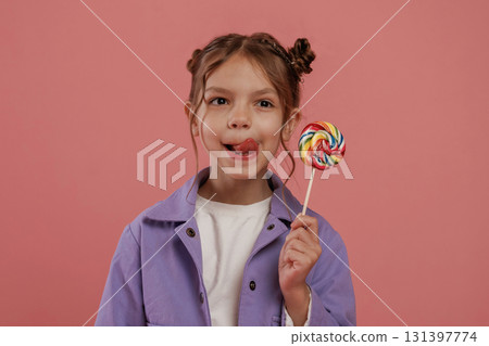 Close up view, with candy. Cute little girl is against pink background 131397774