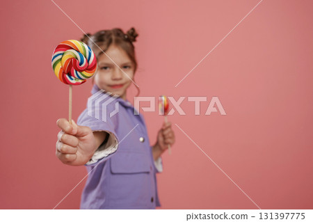 Colorful sweet candies in hand. Cute little girl is against pink background 131397775
