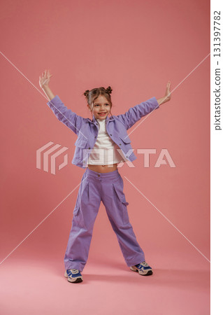 Dancing, having fun. Cute little girl is against pink background 131397782