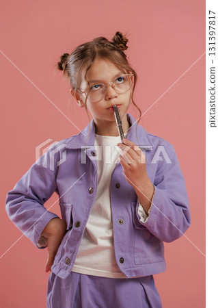 Thinking, holding pen, smart pupil. Cute little girl is against pink background 131397817