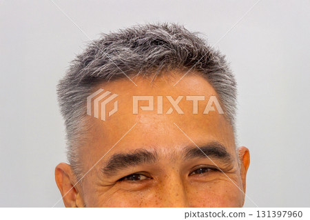 stylish gray haircut of 47-year-old Kazakh man. man with short gray hair is smiling. His skin has warm tone, and he has gentle laughter lines around his eyes stylish gray haircut of 47-year-old Kazakh man. man with short gray hair is smiling. His skin has warm tone, and he has gentle laughter lines around his eyes 131397960