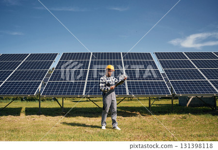 Distant view. Engineer with photovoltaic solar panels outdoors at daytime 131398118