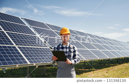 Engineer with photovoltaic solar panels outdoors at daytime 131398130