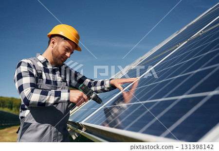 Almost done, installation by using drill. Engineer with photovoltaic solar panels outdoors at daytime Almost done, installation by using drill. Engineer with photovoltaic solar panels outdoors at daytime 131398142