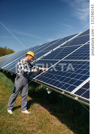 Drill in hand. Engineer with photovoltaic solar panels outdoors at daytime Drill in hand. Engineer with photovoltaic solar panels outdoors at daytime 131398143