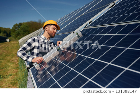 Using the leveler tool. Engineer with photovoltaic solar panels outdoors at daytime Using the leveler tool. Engineer with photovoltaic solar panels outdoors at daytime 131398147