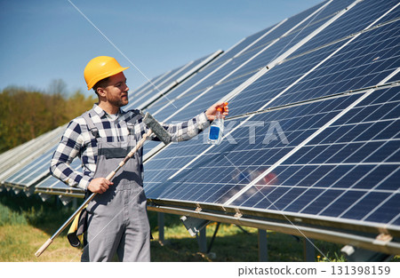 Procedure of cleaning the surface. Engineer with photovoltaic solar panels outdoors at daytime 131398159