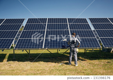 Rear view, the maintenance. Engineer with photovoltaic solar panels outdoors at daytime 131398176