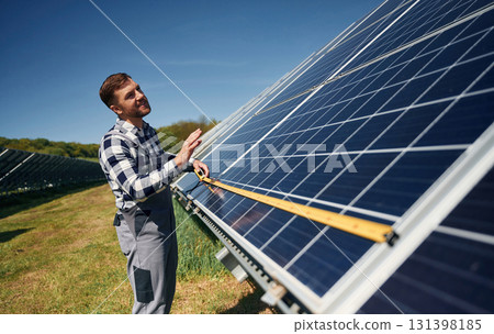 Measuring the width by tape. Engineer with photovoltaic solar panels outdoors at daytime Measuring the width by tape. Engineer with photovoltaic solar panels outdoors at daytime 131398185