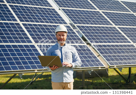 With laptop. Engineer with photovoltaic solar panels outdoors at daytime With laptop. Engineer with photovoltaic solar panels outdoors at daytime 131398441