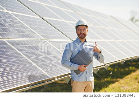 With laptop. Engineer with photovoltaic solar panels outdoors at daytime 131398443