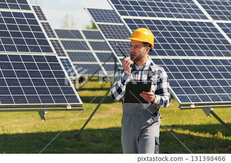 Communication by using walkie talkie. Engineer with photovoltaic solar panels outdoors at daytime Communication by using walkie talkie. Engineer with photovoltaic solar panels outdoors at daytime 131398466