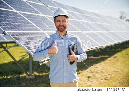 Digital tablet in hand. Engineer with photovoltaic solar panels outdoors at daytime 131398481