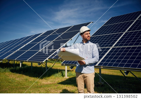 Reading the plan on paper. Engineer with photovoltaic solar panels outdoors at daytime 131398502