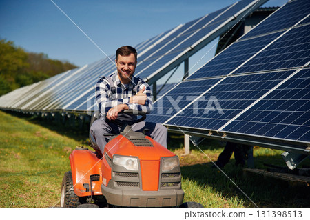 Rides a lawnmower. Engineer with photovoltaic solar panels outdoors at daytime Rides a lawnmower. Engineer with photovoltaic solar panels outdoors at daytime 131398513