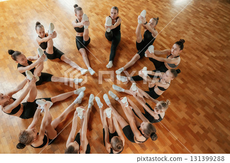 Together in circle on the floor. Group of female kids practicing athletic exercises indoors 131399288