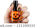 A hand showcases vibrant Halloween nail art featuring a pumpkin-themed polish. The nails have various designs, including dotted patterns and grid lines, perfectly celebrating the season. 131399333