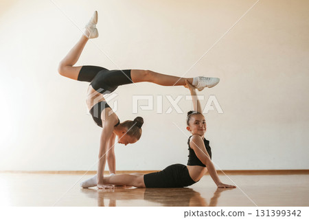 Doing duo practice. Kids are doing athletic exercises indoors together 131399342