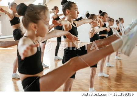 Aerobics conception. Group of female kids practicing athletic exercises together indoors 131399399
