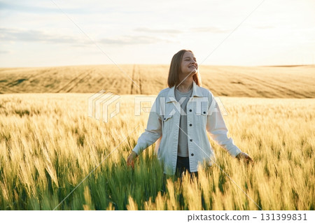 In white clothes, enjoying nature. Young woman is on the beautiful agricultural field at daytime In white clothes, enjoying nature. Young woman is on the beautiful agricultural field at daytime 131399831