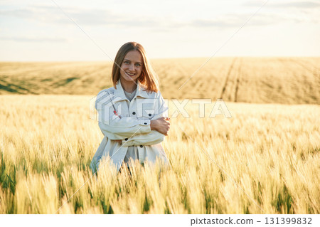 In white clothes, enjoying nature. Young woman is on the beautiful agricultural field at daytime In white clothes, enjoying nature. Young woman is on the beautiful agricultural field at daytime 131399832