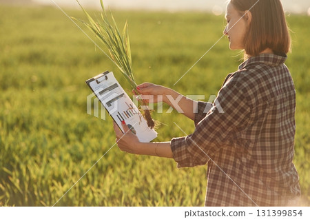 Scientist is checking the plant. Young woman is on the beautiful agricultural field at daytime Scientist is checking the plant. Young woman is on the beautiful agricultural field at daytime 131399854