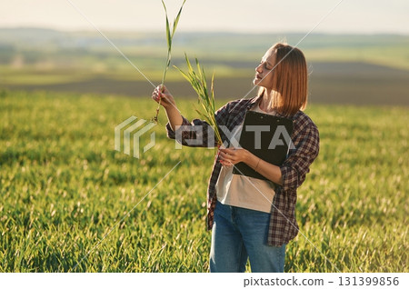 Scientist is checking the plant. Young woman is on the beautiful agricultural field at daytime Scientist is checking the plant. Young woman is on the beautiful agricultural field at daytime 131399856