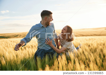 Leading the way, holding hands. Lovely beautiful couple are together on the agricultural field Leading the way, holding hands. Lovely beautiful couple are together on the agricultural field 131399865