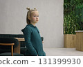 Beautiful little girl wearing green jumpsuit standing in lobby lounge. Adorable child 6 years old 131399930