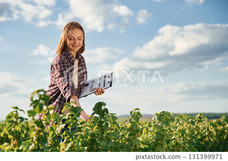 Important data in document. Young woman is on the beautiful agricultural field at daytime Important data in document. Young woman is on the beautiful agricultural field at daytime 131399971