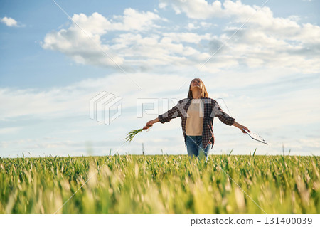 Far view, standing. Young woman is on the beautiful agricultural field at daytime 131400039