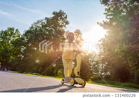 Girl on scooter. Riding child outdoor fun. Sunshine road freedom lifestyle. 131400226