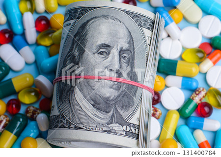 Pack of dollars lay on medicine pills, capsules with hard glance to the camera. Concept of expensive medicine Pack of dollars lay on medicine pills, capsules with hard glance to the camera. Concept of expensive medicine 131400784