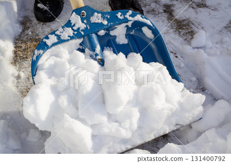 Young man shoveling snow in the driveway near the garage in order to make way for a car 131400792